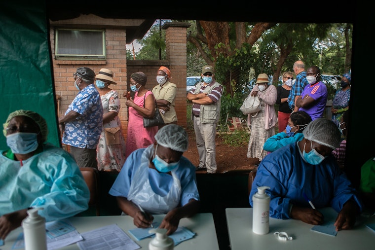 People wait outside a medical tent to receive a COVID-19 vaccine at a hospital in Harare, Zimbabwe, on March 29, 2021. Photo credit: © Tafadzwa Ufumeli/Getty A group of people waiting in line outside of a medical tent