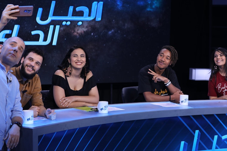 Young debaters pose for a selfie on the set of a TV talk show produced by the Munathara Initiative in Tuni, Tunisia. Photo courtesy the Munathara Initiative A group of people on stage