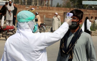 A man in Peshawar, Pakistan, has his temperature taken, on March 18, 2020. Photo credit: © PPI/Zuma/Newscom A person wearing protective gear points a thermometer at a man