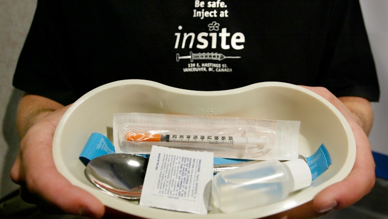 A worker holds a tray and injection kit that will be handed out to drug users as they enter North America's first government-sanctioned injection site for addicts in Vancouver, British Columbia, on September 15, 2003. Photo credit: © Andy Clark/Reuters/Newscom A person holding a tray with supplies